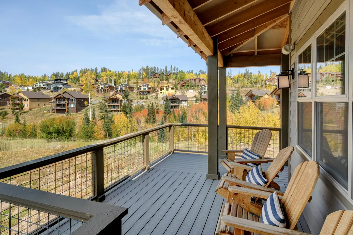 An inviting exterior deck with Adirondack chairs facing a stunning mountain view and autumn foliage, perfect for morning coffee or evening stargazing. The deck embodies outdoor relaxation in all seasons.