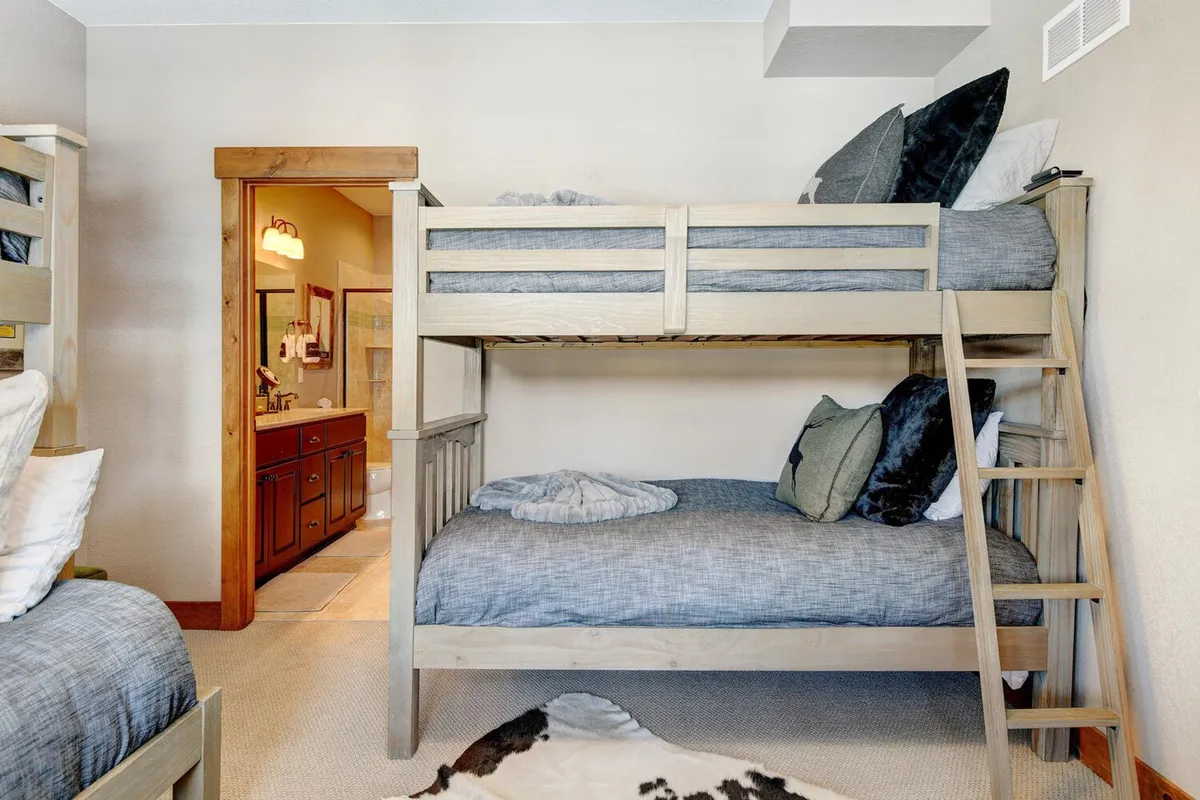 A cozy bunk bed setup with plush bedding and decorative pillows, creating a playful and welcoming atmosphere for kids. The space suggests comfort, nighttime stories, and morning laughter.