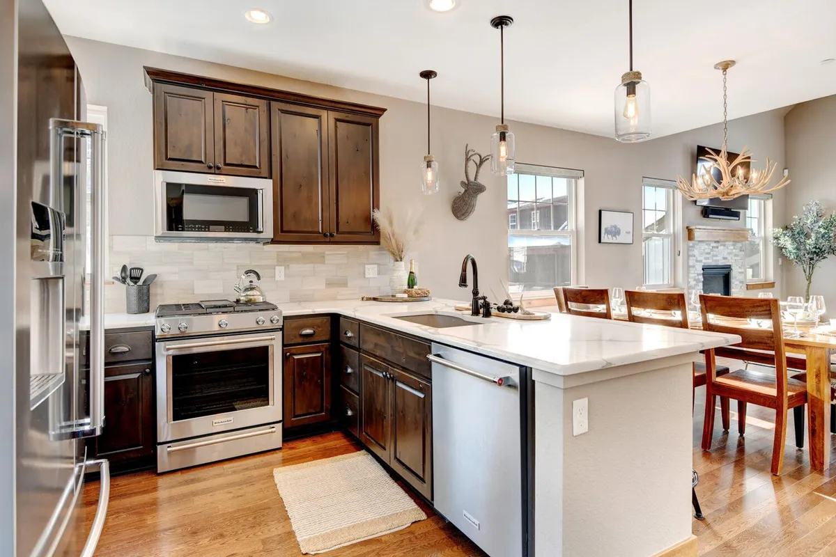 A welcoming open-concept kitchen and dining area featuring a spacious kitchen island, high-end stainless steel appliances, a large dining table with chairs, and expansive windows allowing natural light to fill the space. The atmosphere encourages social cooking and family-style meals.