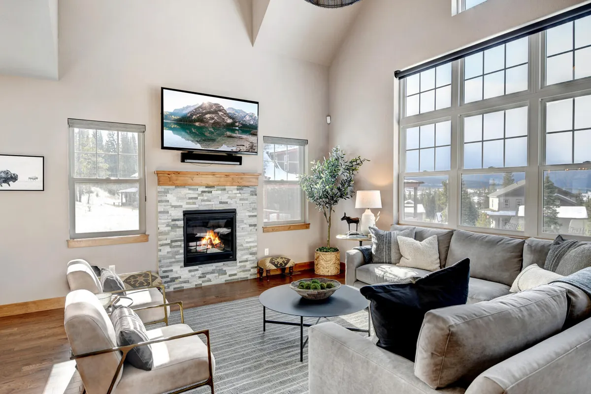 The living area centers on a stylish fireplace, with a large sofa, coffee table, TV, and generous windows that let in plenty of daylight. The scene is arranged for both relaxation and entertainment, fostering intimate gatherings or family movie nights.