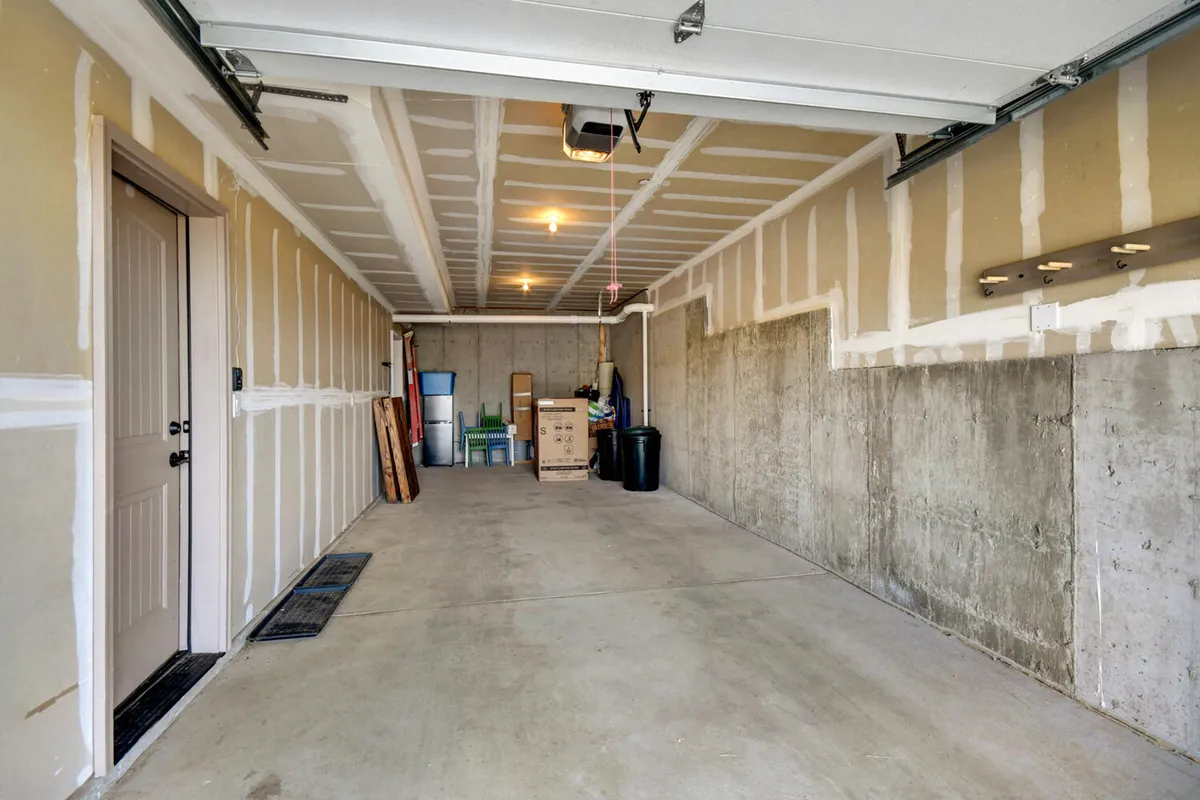 A heated garage with a visible garage door, concrete walls, storage boxes, and chairs—offering ample space for gear storage and preparation for activities.